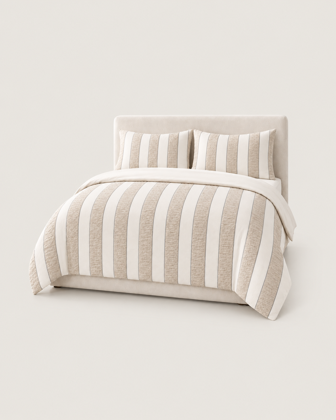 Cream and beige striped pure cotton seersucker bedding on a bed with a plain studio background