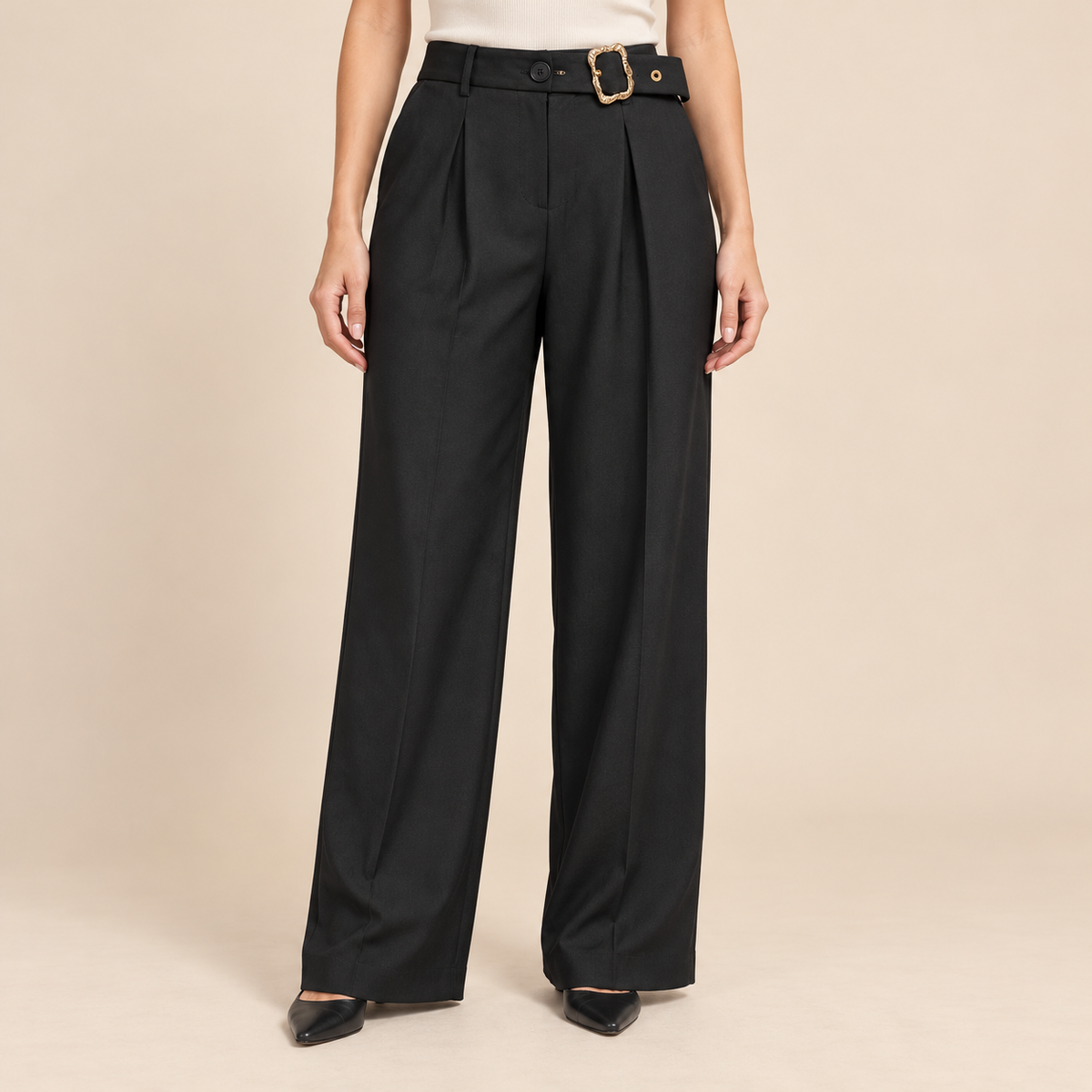 Model wearing black belted pleated trousers with gold-tone buckle